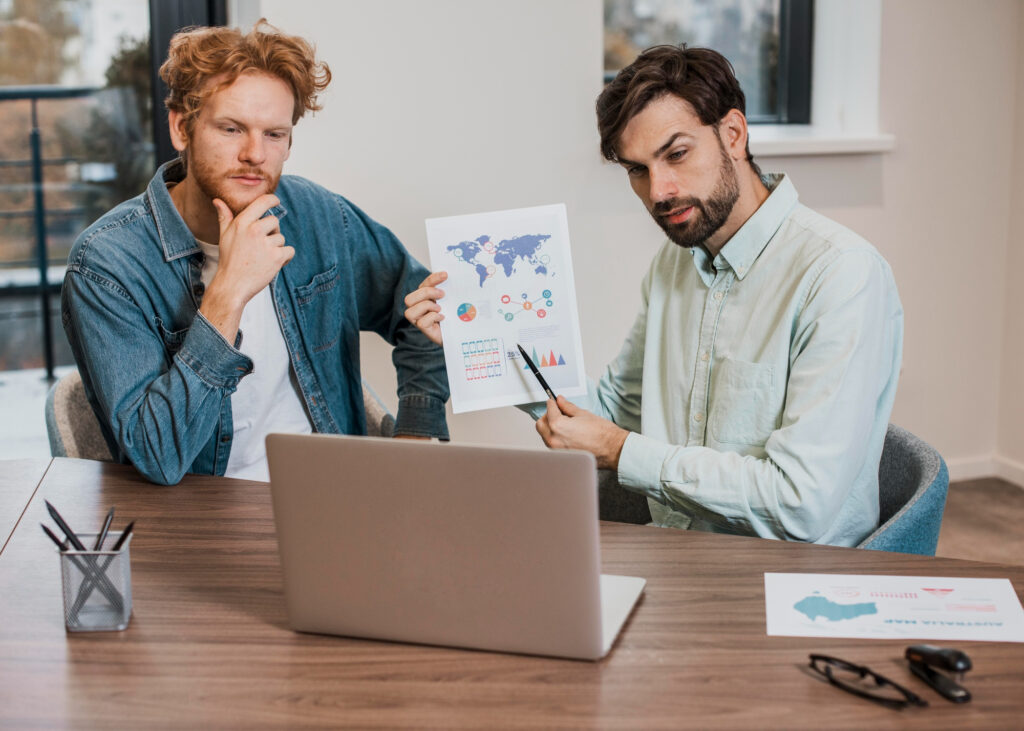 Two Team members discussing global business charts in a casual office setting.