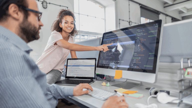 A man and woman focused on a computer, working together on custom web design and development tasks.