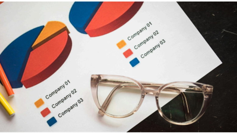 Comparison chart with colorful pie graphs labeled Company 01, Company 02, and Company 03, with eyeglasses and pencils on the table.