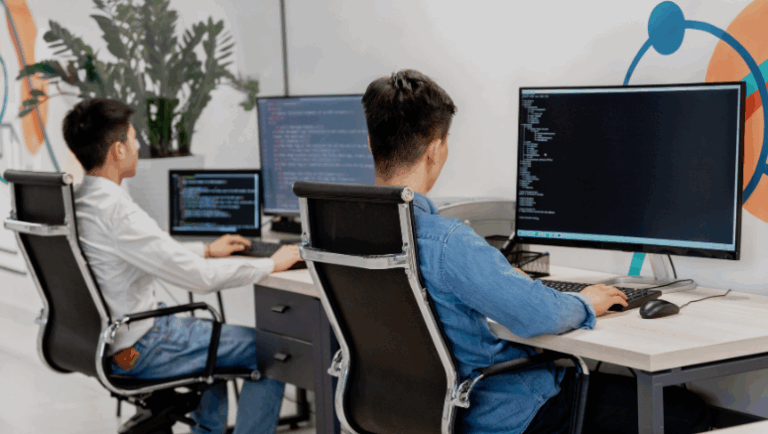 Two men working at desks with computers, focused on software development tasks.